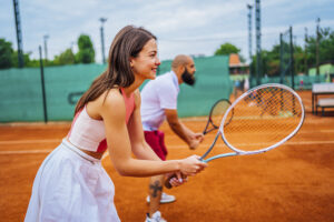 Young cheerful couple playing doubles at tennis